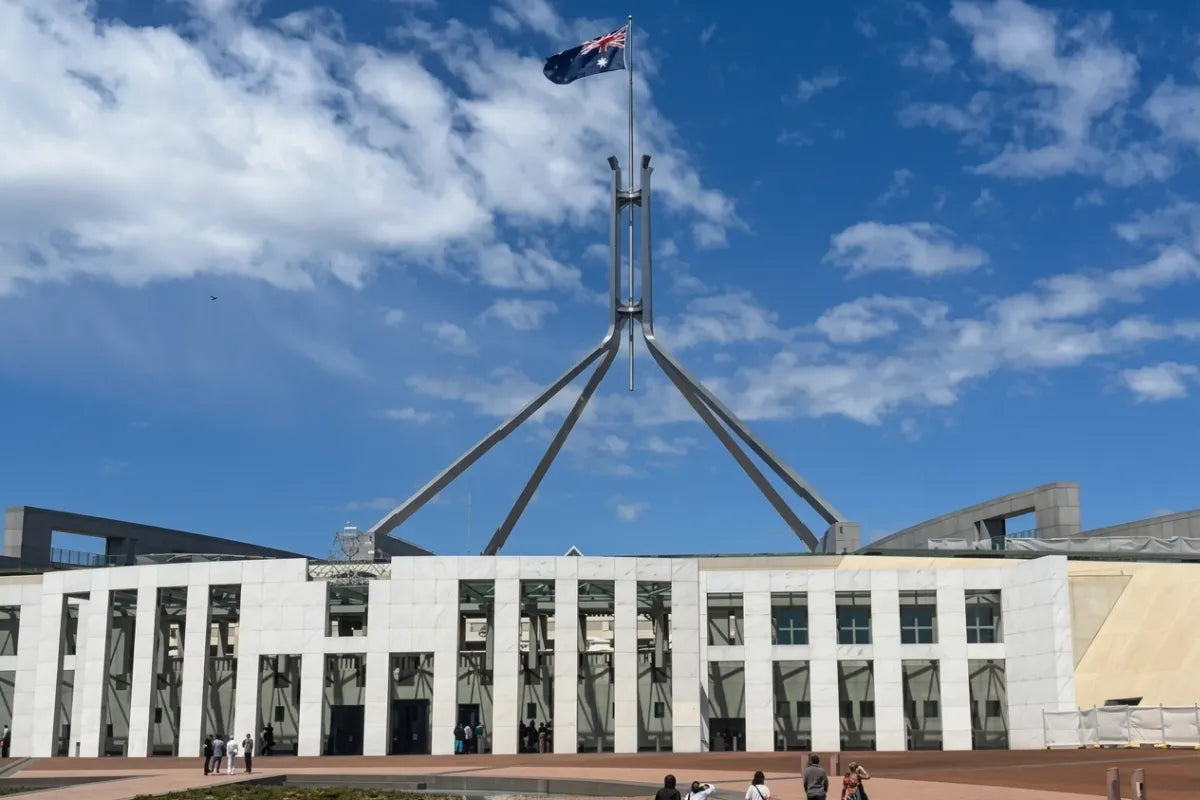 A wide exterior view of Australian Parliament House in Canberra with the Australian flag flying, taken on a sunny day during the Australian Export Awards.