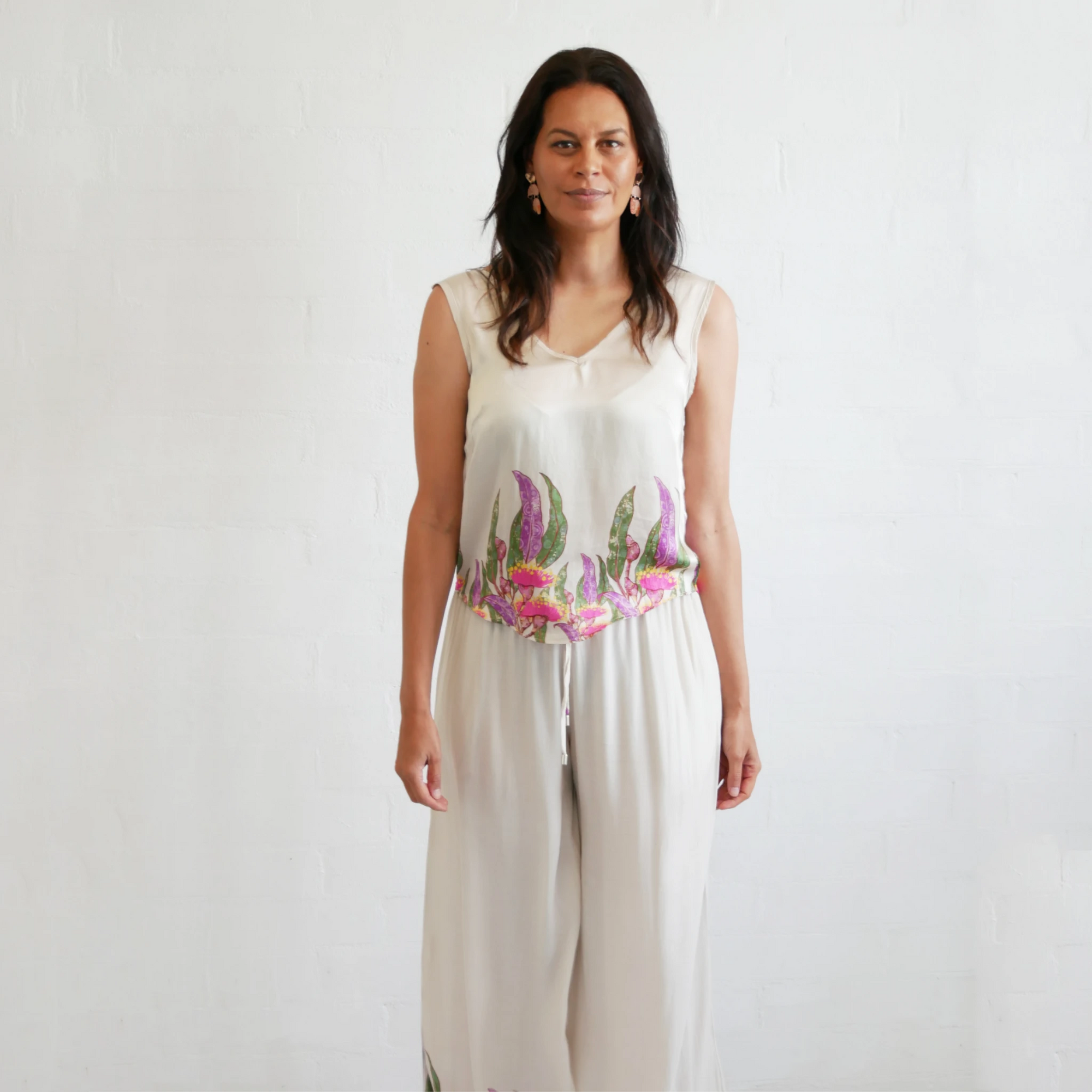 Front view of the Kirrikin Bobbi V-Neck Top in Princess Gum premium viscose satin featuring colorful Indigenous artwork by Buffie Punch.