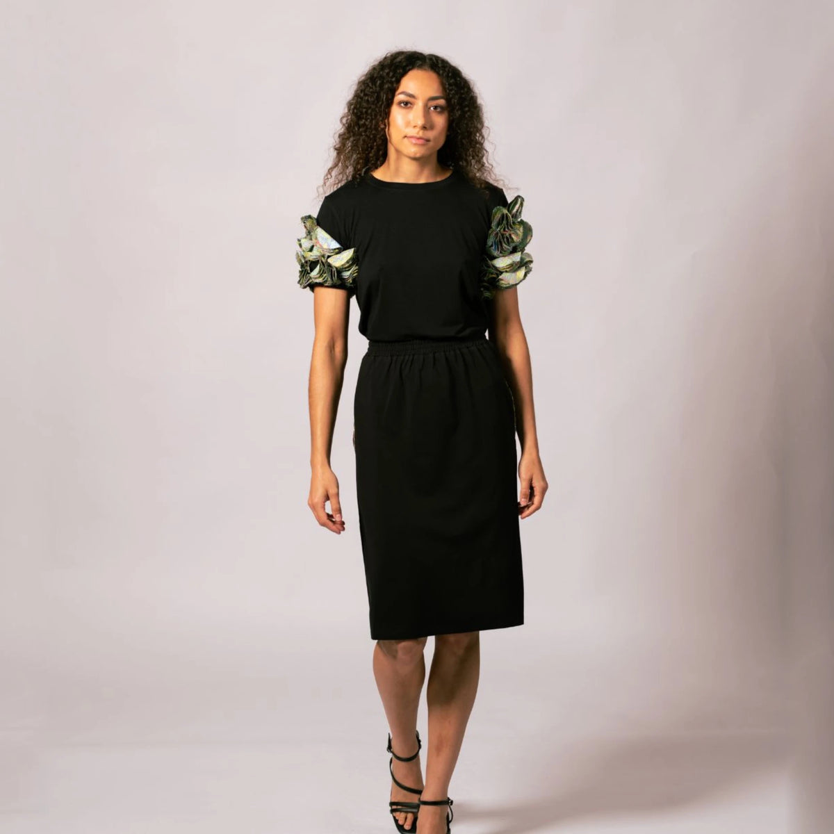 Front full-length view of model wearing the black Emma Gathered Sleeve Top featuring Kimberley Grass artwork ruffled sleeves, paired with a black skirt.