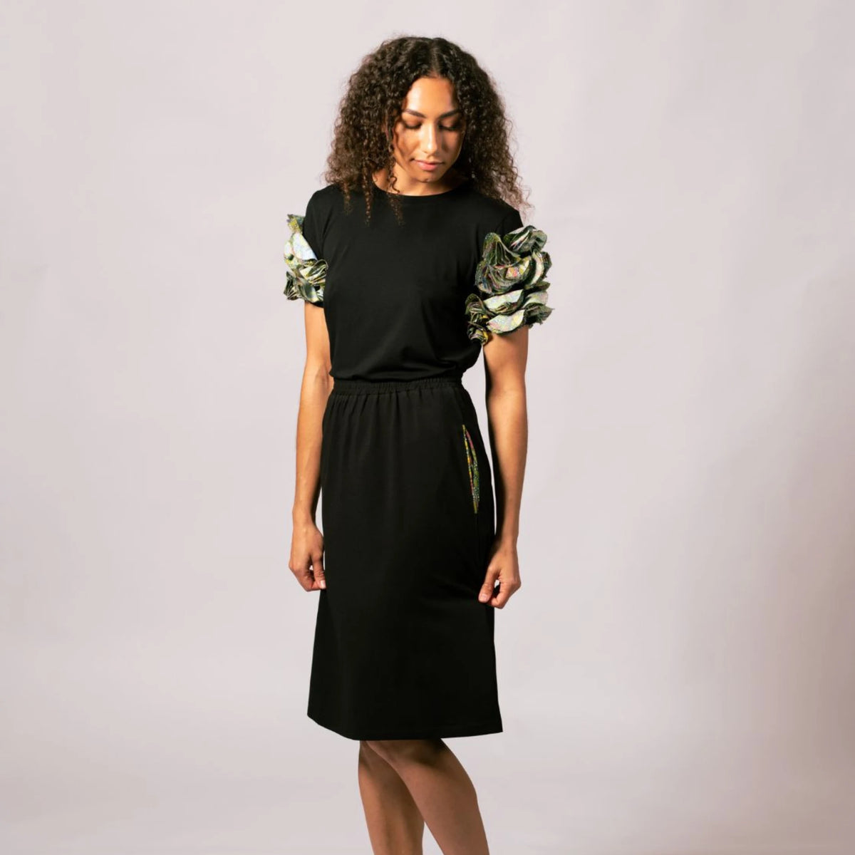 Model looking down wearing the black Emma Gathered Sleeve Top with Indigenous artwork sleeves by Lena Andrews.