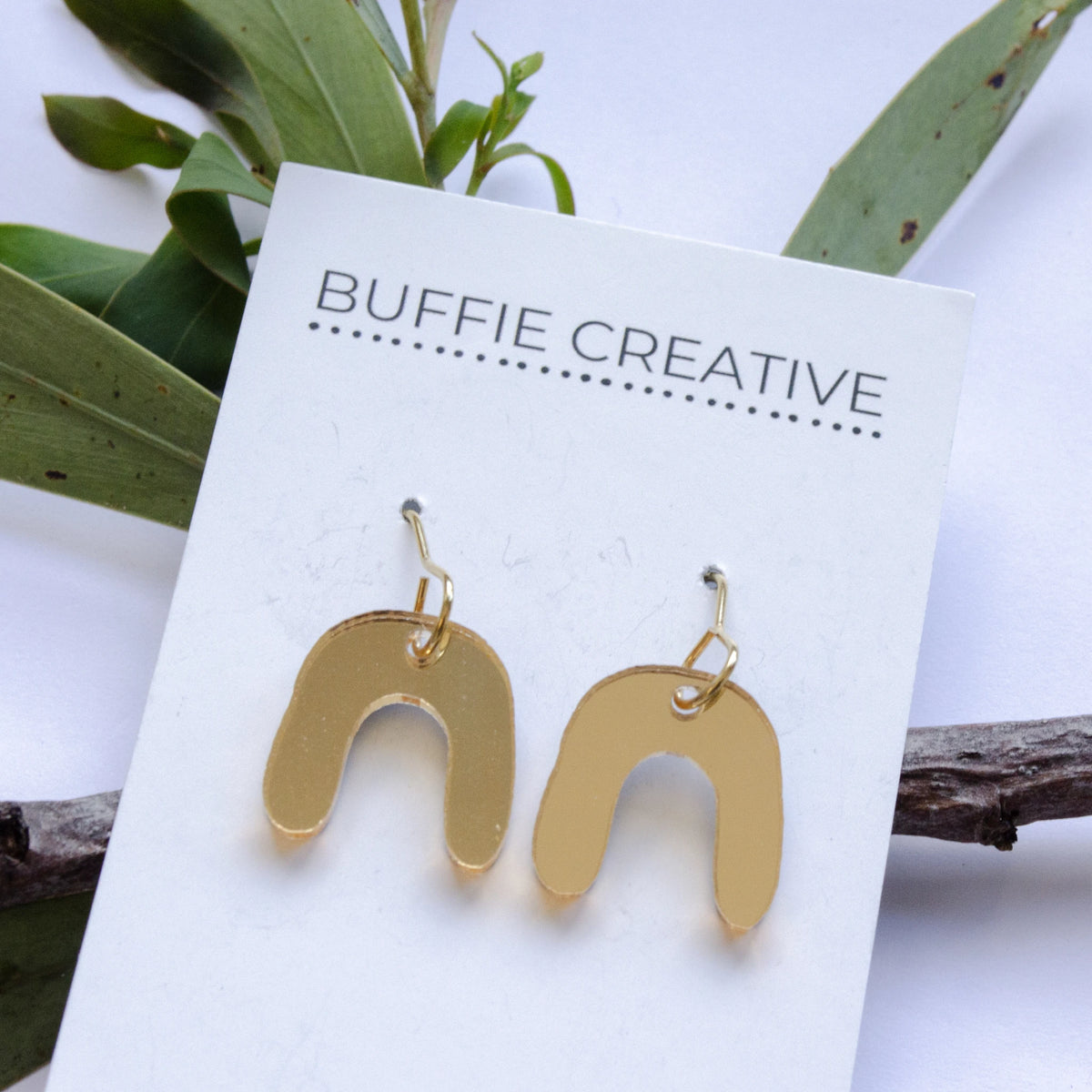 Gold Arch Drop Earrings on Buffie Creative card packaging, featuring a softly curved gold-toned arch design on fish hook wires designed by Buffie Punch.