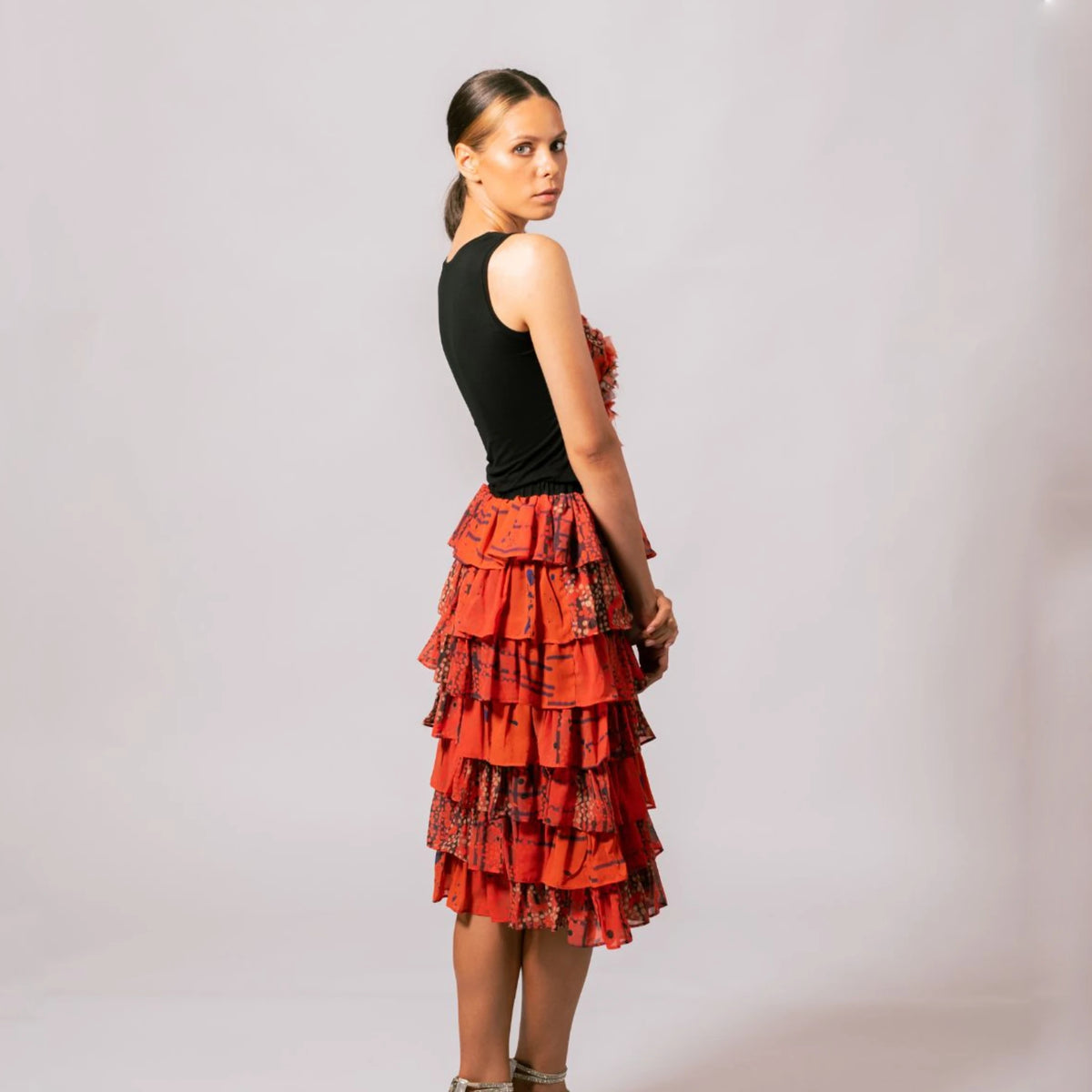 Side profile of model wearing the sleeveless black Lauren Heart Top in Overland Sigh print paired with a matching red-orange skirt.