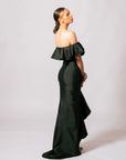 Side profile view of model wearing the black off-the-shoulder Martha evening gown with a flowing ruffled back train.