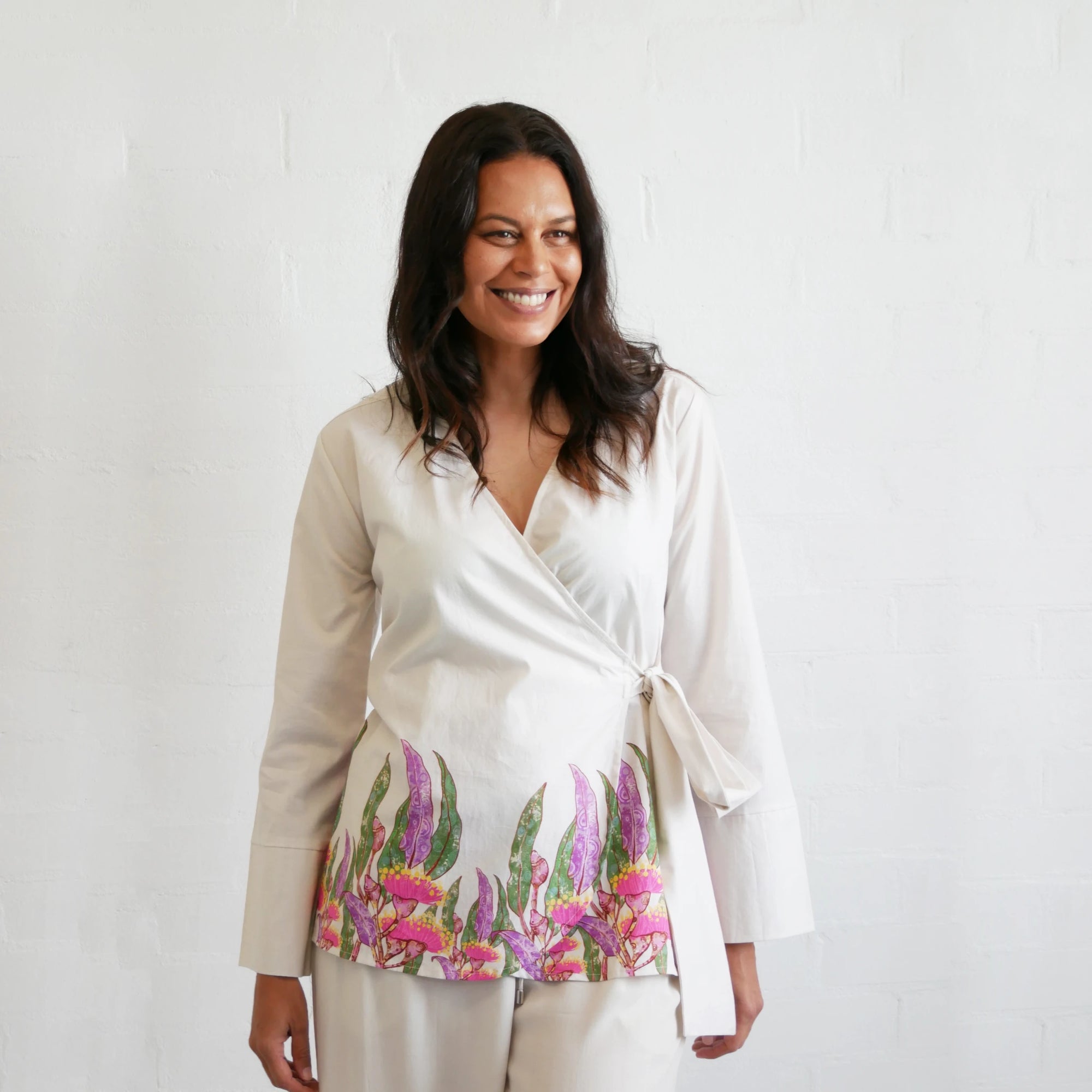 Front view of the Kirrikin Wrap Blouse in Princess Gum featuring soft pink Indigenous floral artwork